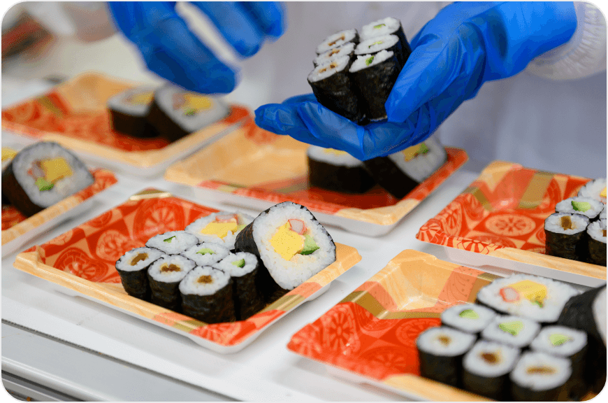 スーパーのおにぎりや巻き寿司やお弁当などを炊飯工場でパッケージする様子